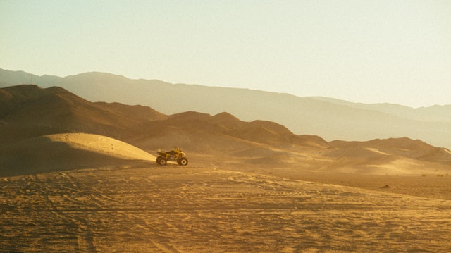 Štvorkolka zaparkovaná na piesku na púšti.jpg